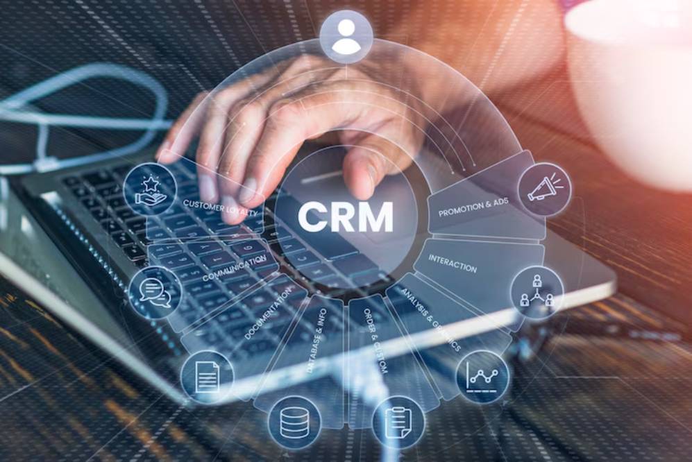 A hand typing on a laptop surrounded by CRM-related icons, representing customer engagement and management strategies.