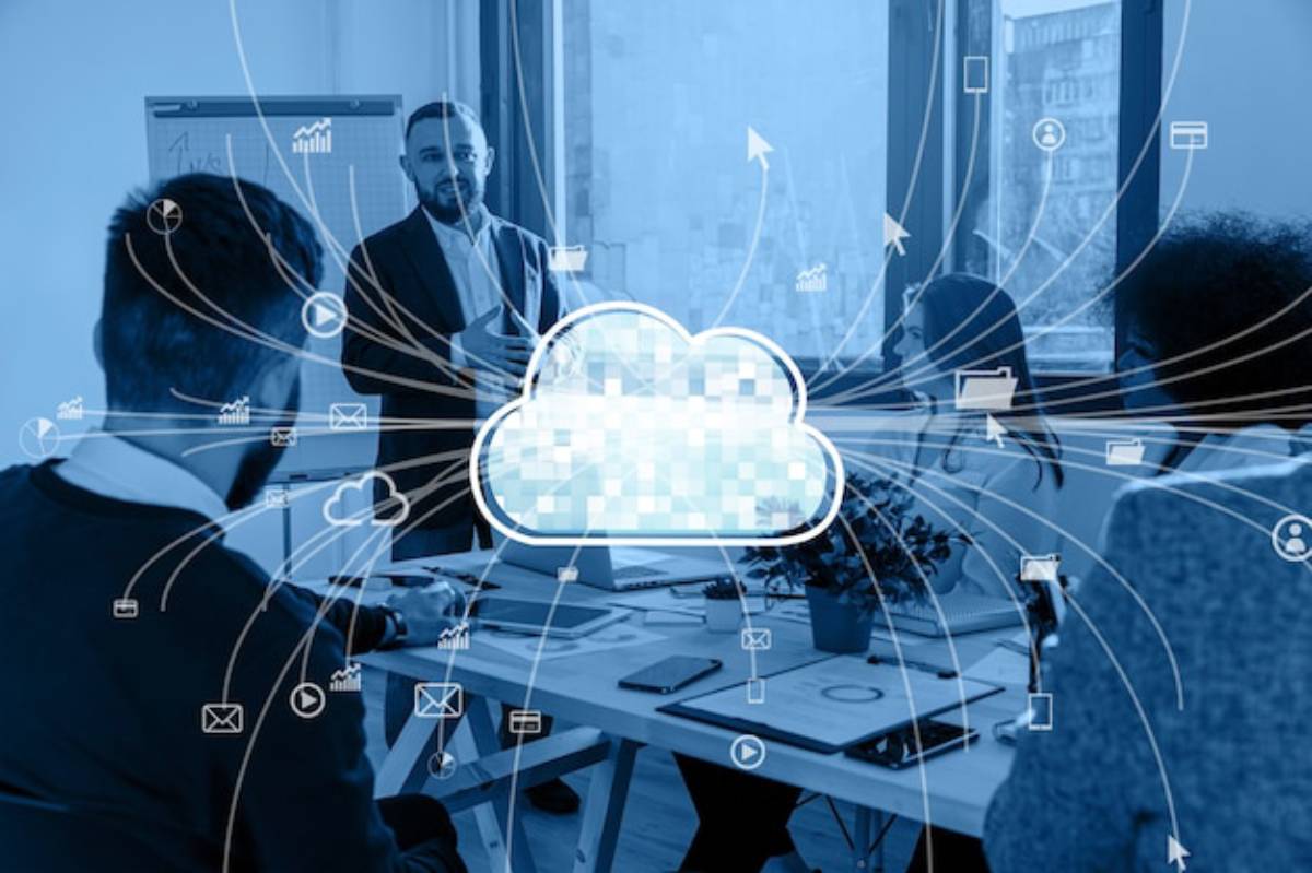 A business meeting with individuals engaged around a table, featuring a cloud symbol surrounded by digital icons representing data and connectivity.