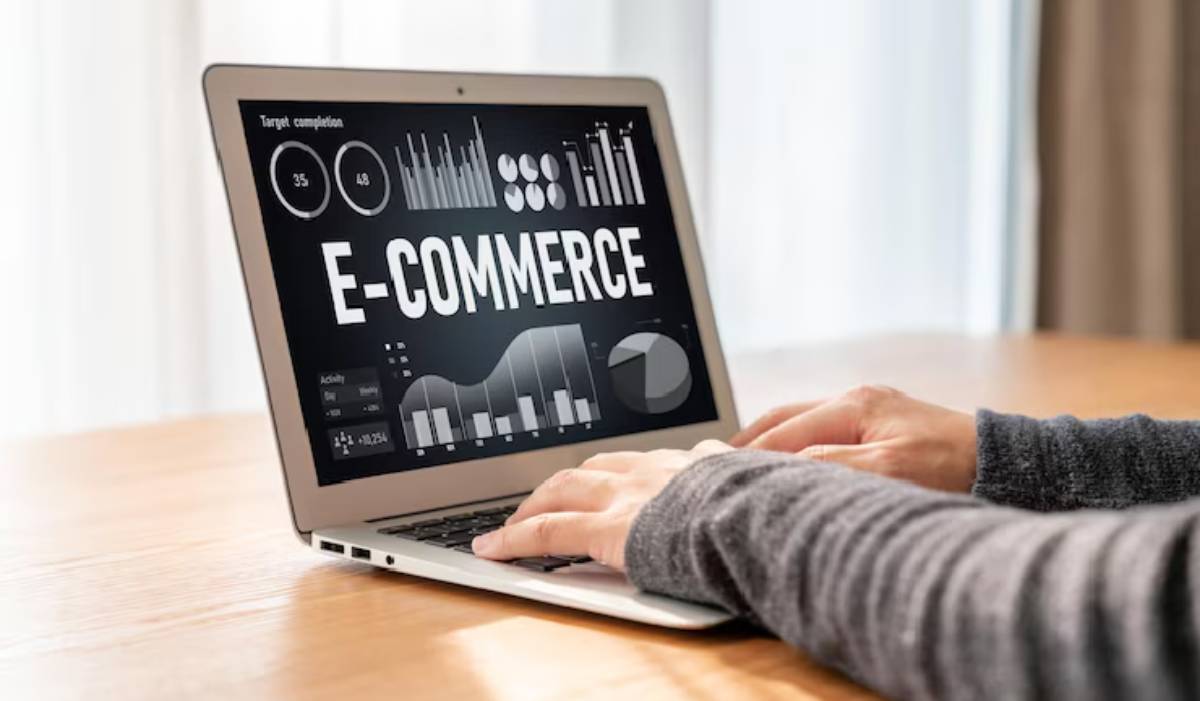 A person typing on a laptop displaying e-commerce analytics, including graphs and statistics on a dark background.