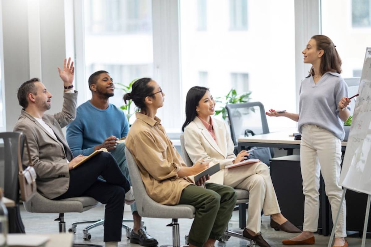 A group of diverse professionals in a modern office actively engaging in a meeting, with one person presenting ideas.