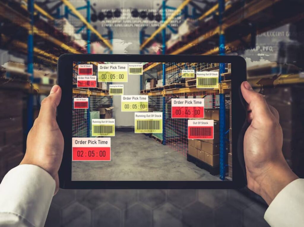 A person holds a tablet displaying a warehouse with real-time stock status and order pick times overlaid on inventory items.
